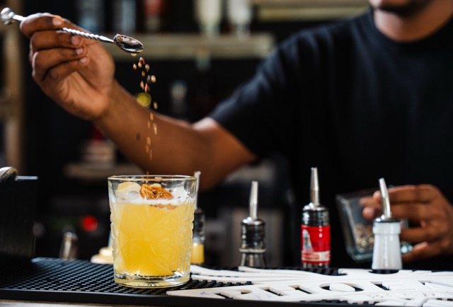 A bartender dusting spices over a cocktail at Amigo Bar & Bistro