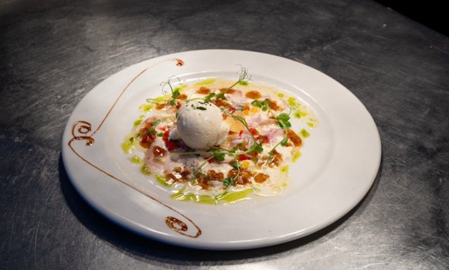 Thinly sliced raw fish with lemon sorbet, served at Amigo since 1985