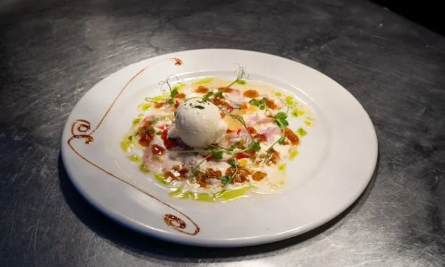 Thinly sliced raw fish with lemon sorbet, served at Amigo since 1985